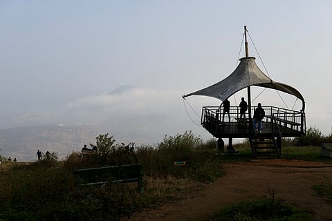 People take in the sunrise from a viewpoint at the summit of the hill